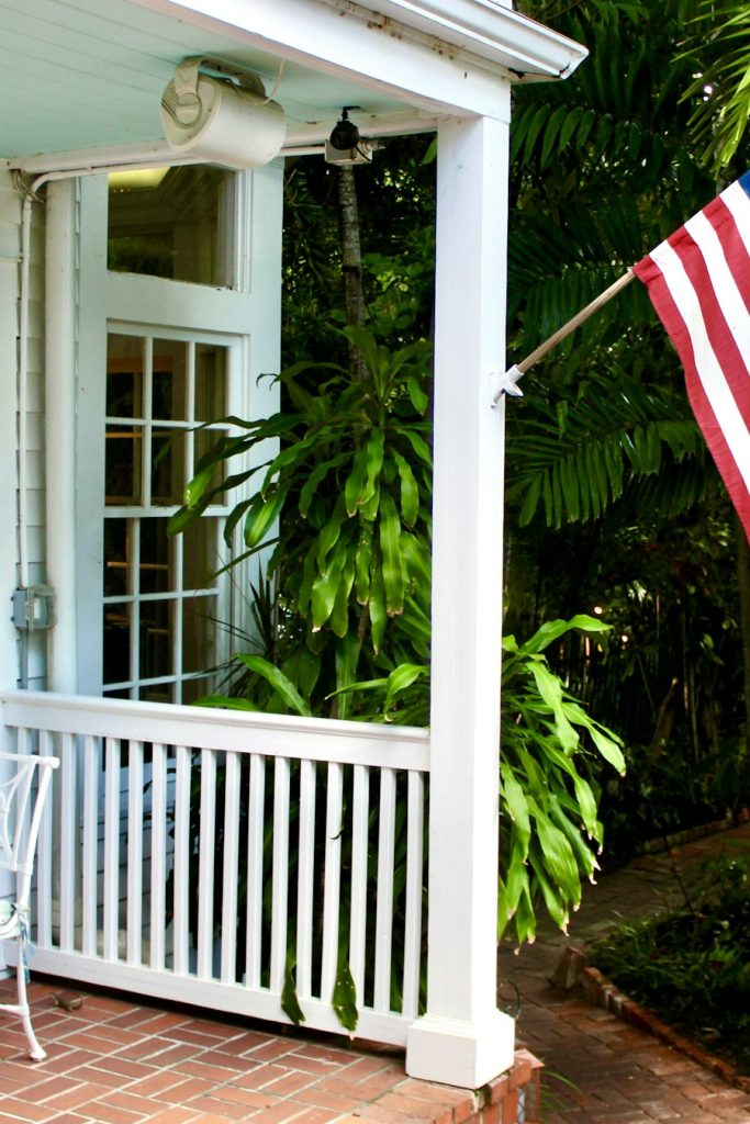 Front porch with white railings, French doors and tropical plants