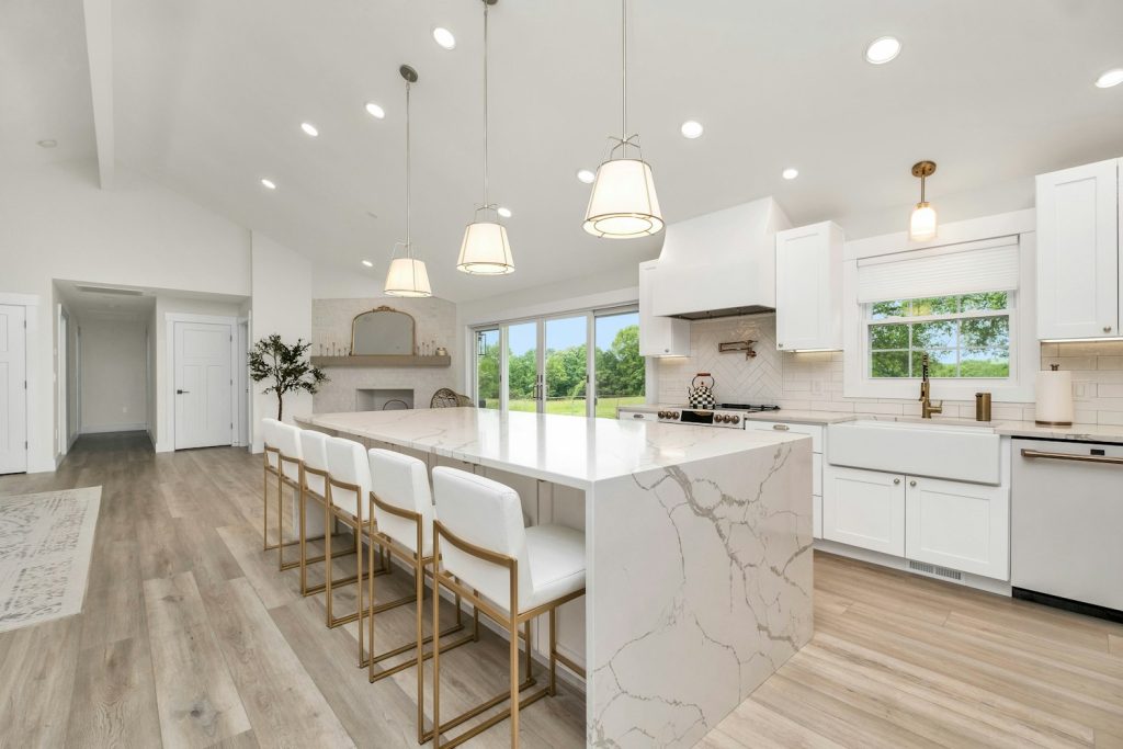 Bright white kitchen with a marble island and bar stools