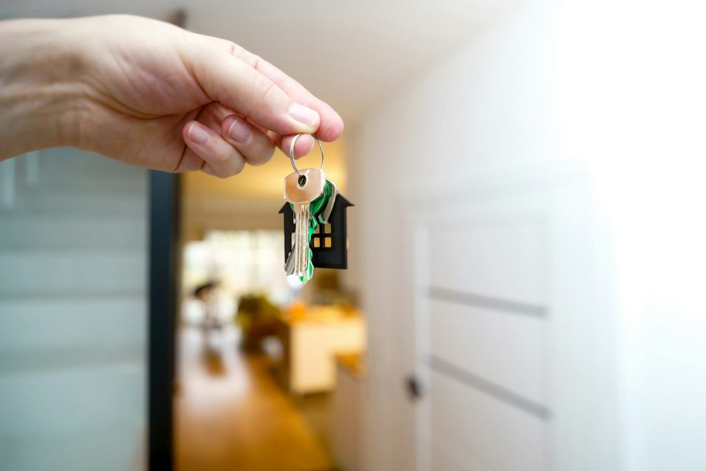 Hand holding house keys in an open doorway