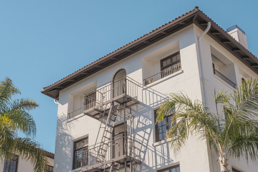 Small white stucco apartment building with palms