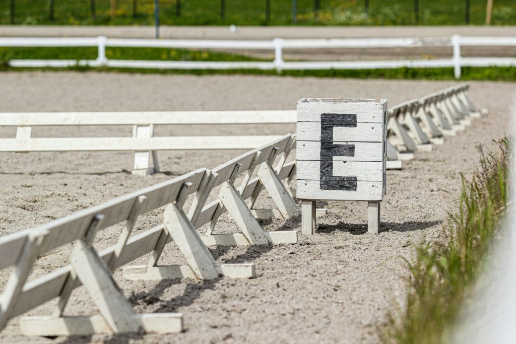 Dressage arena letter marker on white rail fencing