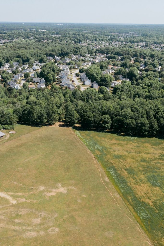 Aerial view of open pasture bordered by woods