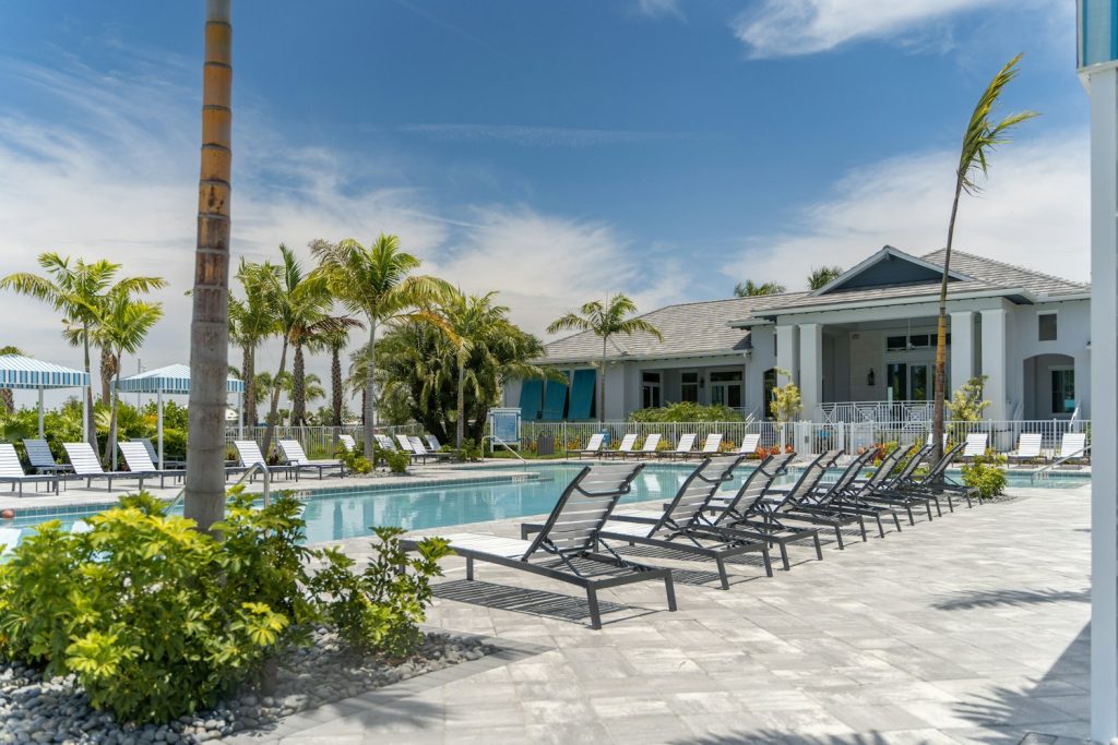 Community pool with lounge chairs, palms and a clubhouse